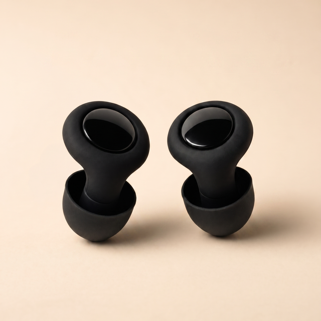 A pair of Quiet earplugs in soft silicone, standing on a warm paper surface