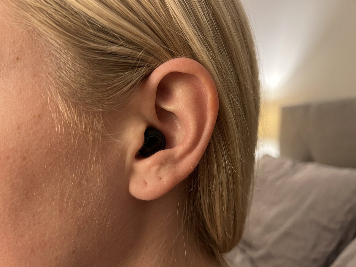 Close-up of a Quiet earplug seated flush in a woman's ear, sitting below the ear rim