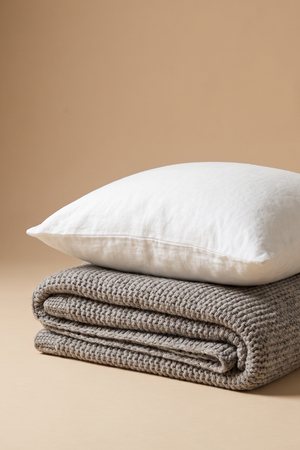 A folded blanket and a pillow, the spare bedding carried to another room